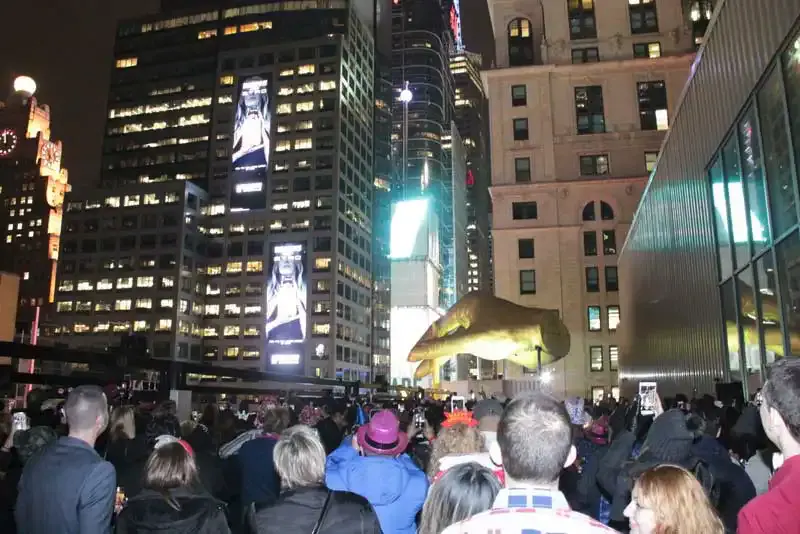 Crowd gathered at night in Times Square below lit billboards and skyscrapers on 42nd Street