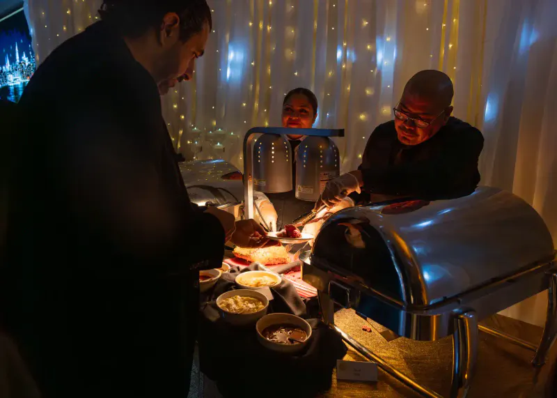 Guests served from chafing dishes at a New Year's Eve gala buffet in front of a fairy-light curtain