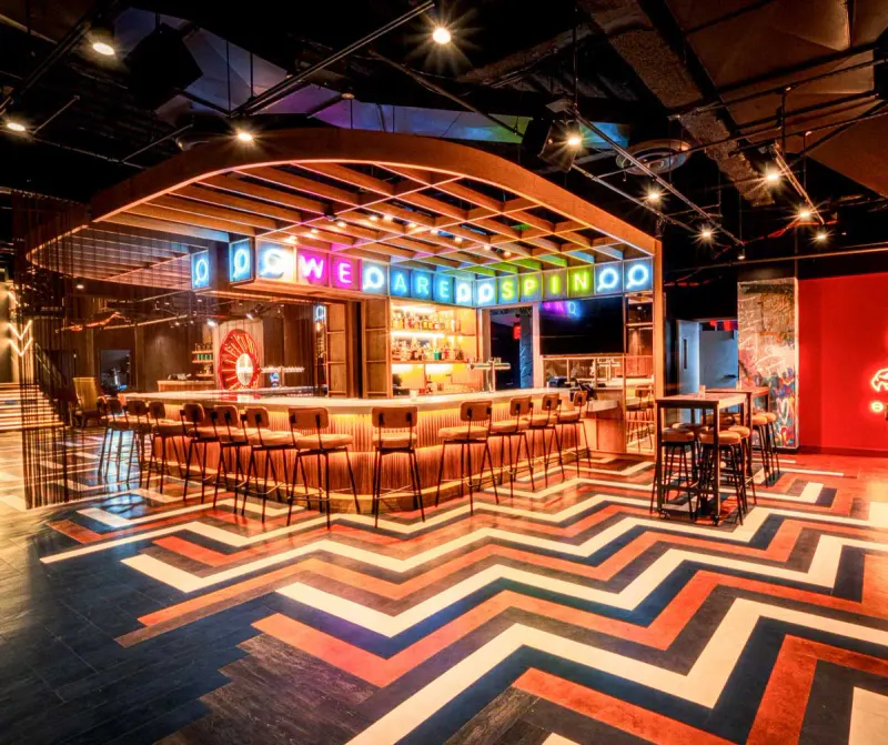 Bar at Spin NYC Times Square with neon marquee sign, bar stools and bold chevron floor