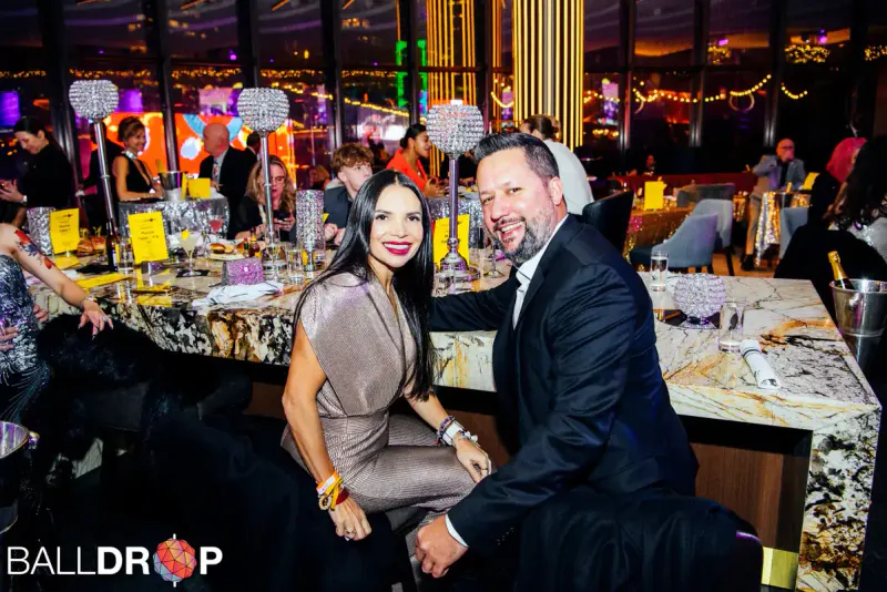 Couple in formal wear seated at a marble bar with crystal candlesticks at the Marriott Marquis New Year's Eve gala