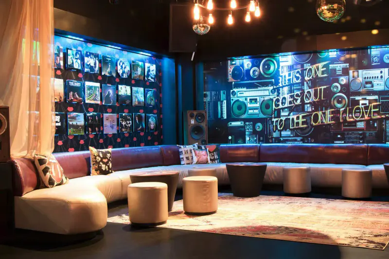 Lounge at Frames in Times Square with curved leather banquettes, ottomans, neon boombox mural and record wall