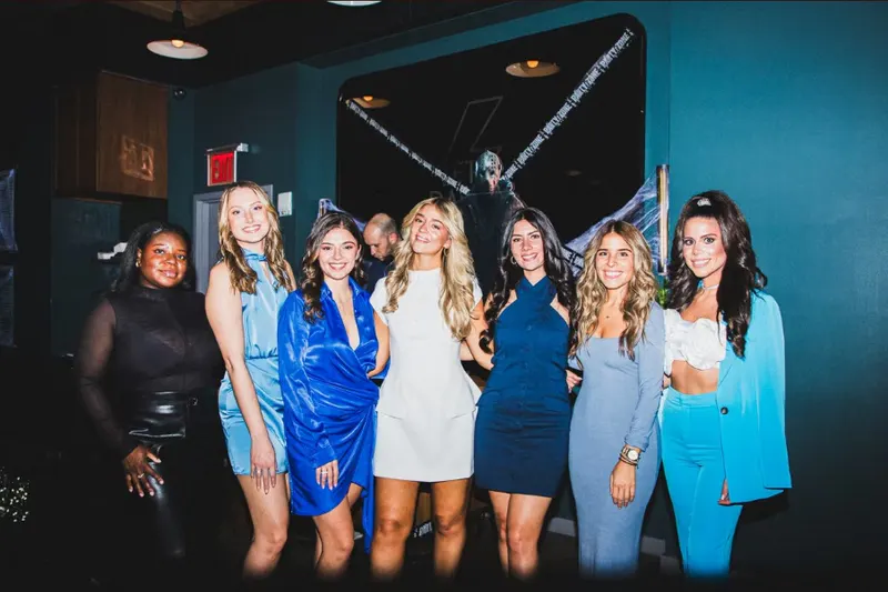 Group of friends in blue and white party dresses posing together at a nightclub in NYC
