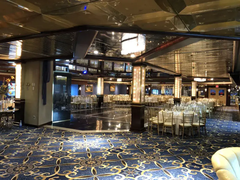 Banquet hall on the Cornucopia Majesty with round tables, gold chairs, mirrored ceiling and a polished dance floor