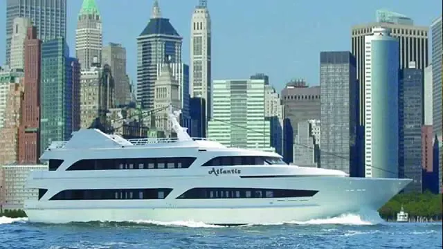 The Atlantis yacht cruising past the Lower Manhattan skyline on a clear day in NYC