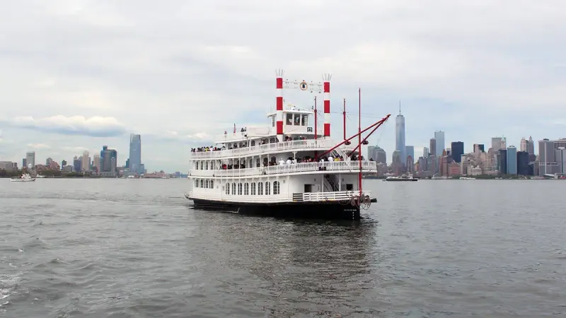 Liberty Belle paddlewheel party cruise boat on the Hudson with guests on deck and the Lower Manhattan skyline behind