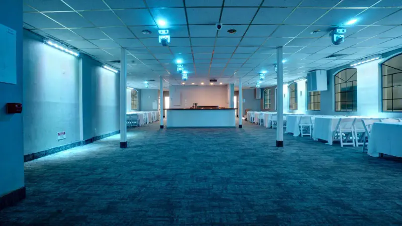 Empty event deck on the Liberty Belle party cruise with blue lighting, open dance floor and white-draped tables by the
