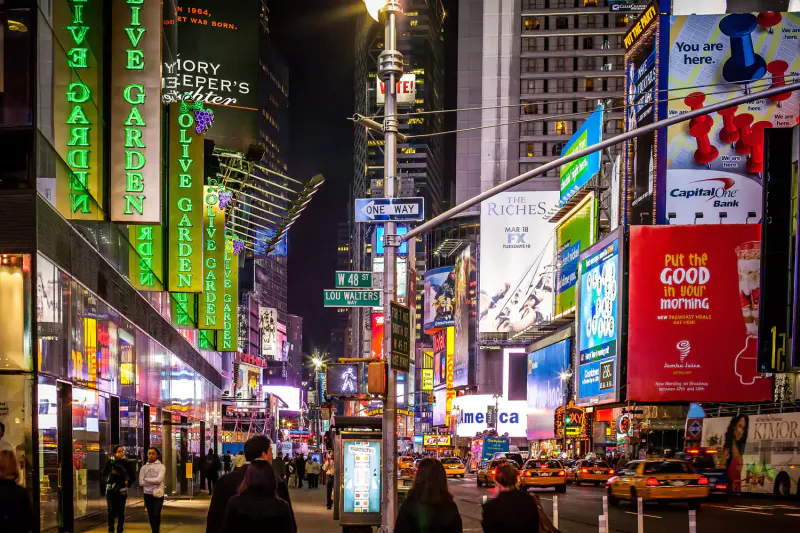 Times Square at night with glowing Olive Garden neon signs, billboards, yellow taxis and pedestrians on West 48th Street