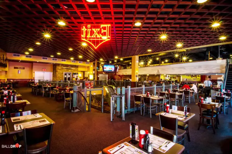 Dallas BBQ Times Square dining room with red neon sign, set tables and railings under warm ceiling lights