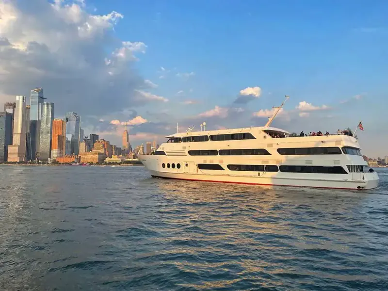White party yacht cruising the Hudson with guests on the top deck and the Manhattan skyline behind