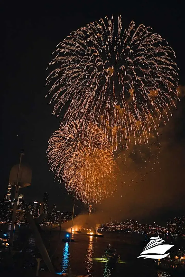 July 4th fireworks bursting in gold over the NYC waterfront with boats and skyline lights below