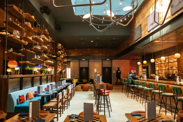 Dining room at Recreation with teal banquette, bar stools, open shelving and glowing pendant lights