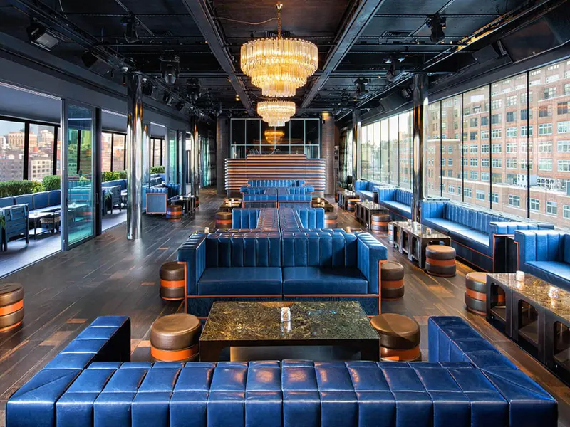 Rooftop lounge with blue leather banquettes, crystal chandeliers and floor-to-ceiling windows overlooking NYC