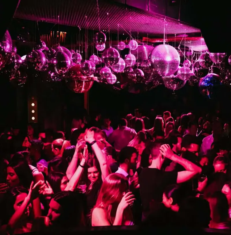 Packed nightclub dance floor under a ceiling of disco balls in pink lighting at Loosies Nightclub