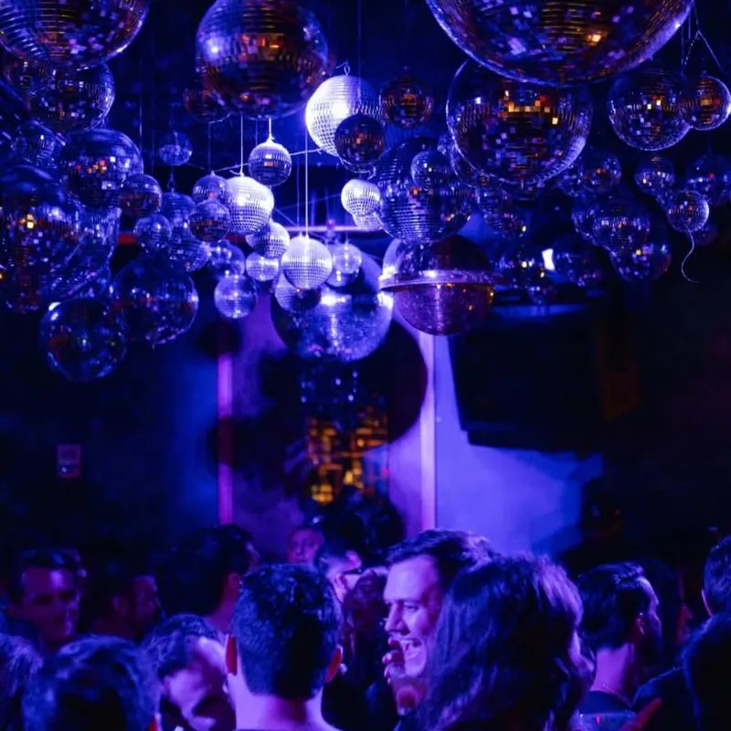 Crowd under a ceiling covered in disco balls in purple light at Loosies Nightclub